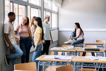 Diverse young high school students hanging out in classroom during break. Education concept