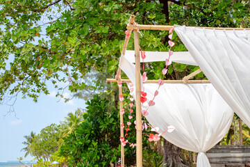 Romantic bamboo gazebo with white canopy decorated with hearts on the shore of a tropical island
