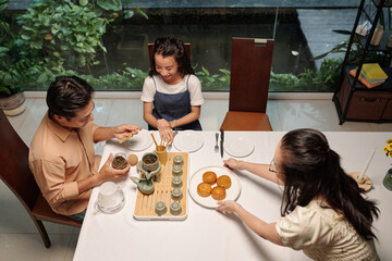 High angle view of Asian family celebrating autumn holiday with tea and moon cakes