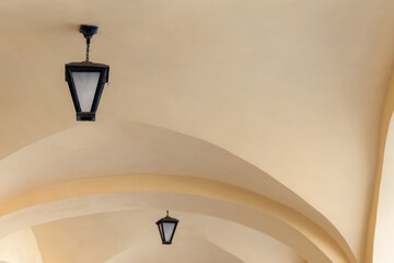 Vintage forged lamps are mounted at white arched ceiling