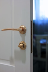 Obraz premium A White Door Slightly Ajar Reveals A Cozy Room Interior, Featuring A Sleek Brass Handle And Subtle Lighting. This Image Conveys Warmth, Privacy, And Inviting Space.