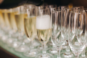Alcohol setting on catering banquet table, bartender pouring liquor beverages, row line of different colored alcohol drinks on a party, glass of wine, sparkling wine on decorated banquet table event