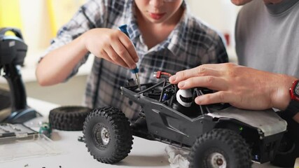 A Father and His Son Enjoying a Fun and Engaging Time Building a RemoteControlled Car Together. Close-up of hands and details in the frame.