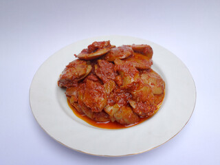 Jengkol Balado or dogfruit with red chili sauce, a spicy traditional Indonesian dish from West Sumatra, served on a white plate with a clean white background