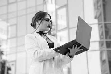 Stylish Businesswoman in Pinstripe Suit Collaborating with Laptop Outside Modern Building