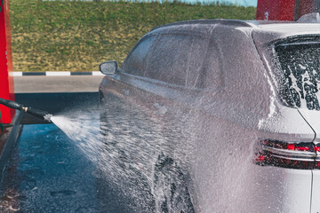 Сar wash self-service. Man washing luxury vehicle with white foamy detergent. Automobile cleaning...