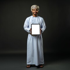 young omani man in white thobe holding tablet isolated on dark background