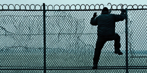 A man climbs over the fence. Creative concept of illegal migration and border crossing