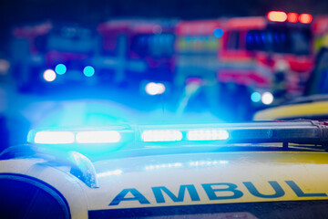 Close-up of flasher on roof of ambulance car of emergency medical service on road against fire engines. Themes rescue, accidents and disasters..