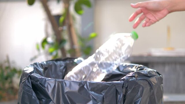 Hand of people sort waste plastic water bottles and throw them into the trash can to separate waste for recycle 