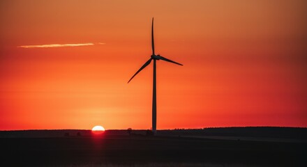 Wind turbine silhouette at sunset in rural landscape