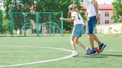 Conception of soccer game. Father and little daughter are playing and having fun outdoors.