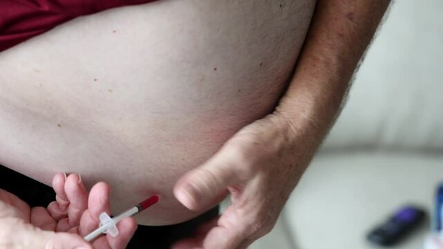 Man preparing to inject diabetes or weight management medication into his abdomen using a syringe, focusing on the injection process and hand placement.
