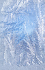 Frost patterns on frozen glass on a winter day. Winter frosty texture natural background