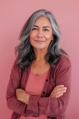 Fototapeta premium Confident Mature Woman with Gray Hair and Pink Attire on Pink Background