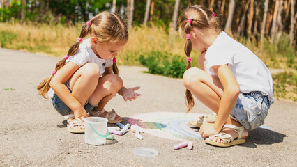The child draws a a rainbow on the asphalt with chalk. Selective focus. Kids.