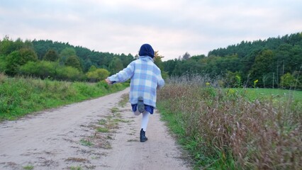 Obraz premium Young Happy Caucasian Kid Girl in Warm Jacket Running Down Country Road on Autumn Day