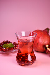 Turkish pomegranate tea in a glass glass and fresh pomegranate. Fresh mint and pomegranate seeds on the surface.