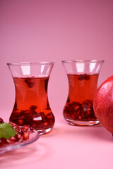 Turkish pomegranate tea in a glass glass and fresh pomegranate. Fresh mint and pomegranate seeds on the surface.