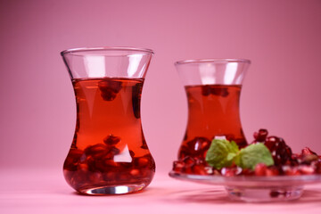 Turkish pomegranate tea in a glass glass and fresh pomegranate. Fresh mint and pomegranate seeds on the surface.