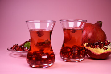 Turkish pomegranate tea in a glass glass and fresh pomegranate. Fresh mint and pomegranate seeds on the surface.