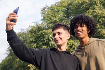multiethnic group of two male teens smiling happy taking selfie photo with mobile phone, concept of...