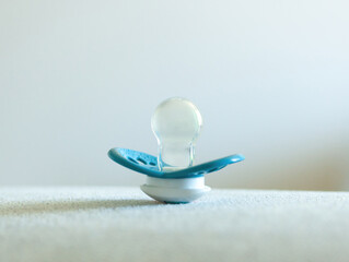 Blue baby pacifier resting on a white carpet