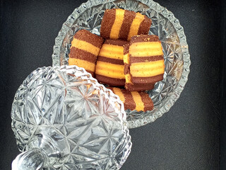 A crystal jar filled with delicious, striped cookies. The cookies, featuring alternating layers of chocolate and vanilla, look incredibly tempting. The jar's lid is partially open.