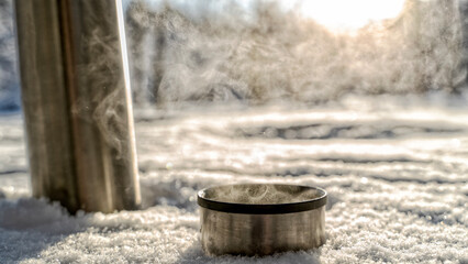 Fototapeta premium thermos with hot tea or coffee in the winter forest