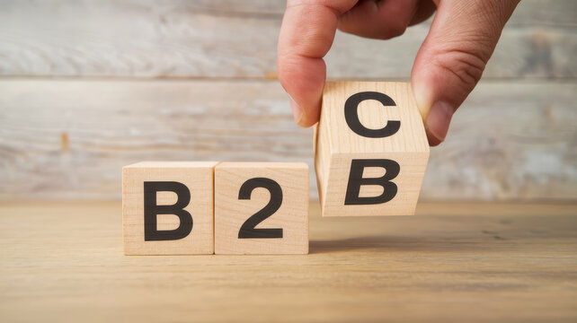 Hand placing wooden block with B2B and C on a table, representing business concepts.