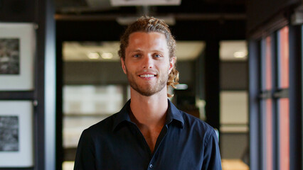 Portrait Of Smiling Young Businessman Working In Modern Open Plan Office