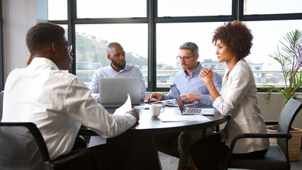 Multi-Cultural Business Team Meeting Collaborating Sitting Around Table In Modern Office Together