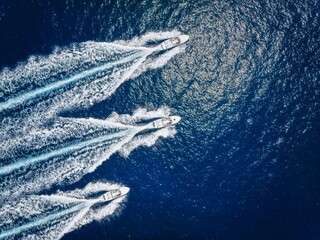 Aerial top down view of three motorboats racing over the ocean with high speed