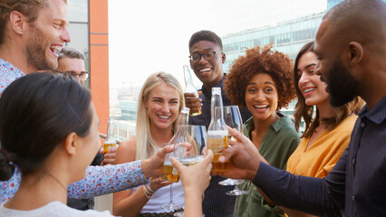 Multi-Cultural Business Team Celebrating Outdoors For After Work Drinks On Office Rooftop Or Bar