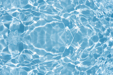 Blue water with ripples on the surface. Defocus blurred transparent blue colored clear calm water surface texture with splashes and bubbles. Water waves with shining pattern texture background.