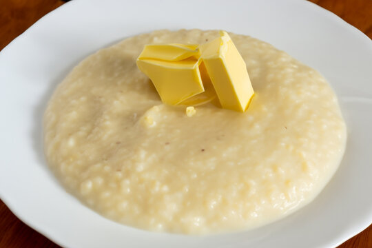 Plate of white porridge with semolina and spoon. food sweet healthy concept. a white plate with a piece of porridge, butter, and semolina. a plate of breakfast with a piece of white and semolina and.