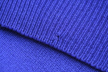 Close-up of a darned hole in a purple woollen fabric, darned hole in a sweater 