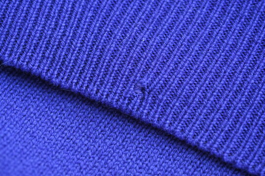 Close-up of a darned hole in a purple woollen fabric, darned hole in a sweater 