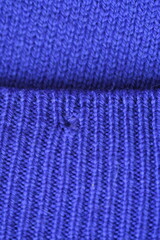 Obraz premium Close-up of a darned hole in a purple woollen fabric, darned hole in a sweater 