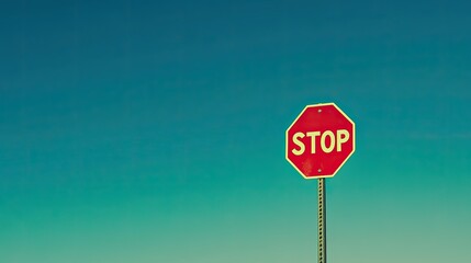 A bold red stop sign against a clear blue sky, standing as a symbol of caution and attention.