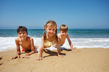 Joyful kids on sandy beach with bright sea and clear blue sky