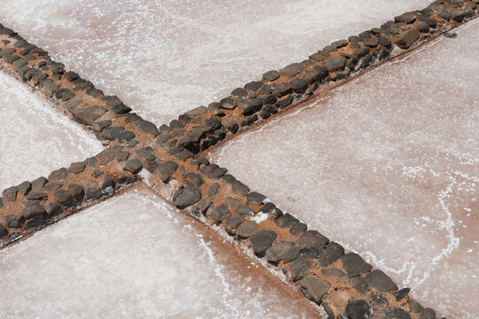 Traditional salt pans with crystallized salt and volcanic stones