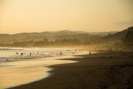 Misty beach sunset in El Salvador with people enjoying the surf
