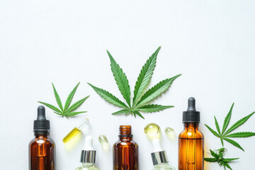Cannabis oil bottles arranged on wooden surface with natural light casting shadows, various sizes and colors, ready for use.