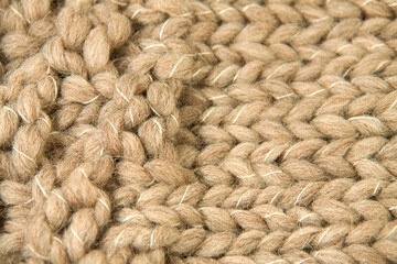 Texture of thick wool woven in light brown color. The wool follows two directions and white thread can be seen