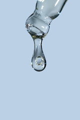 Pipette with serum, gel, oil or other cosmetic product with falling drop. Macro closeup