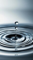 A close-up of a water droplet creating ripples on the surface of still water, showcasing fluid motion and tranquility.