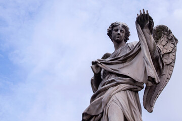 Stone sculpture of angel raising his hand in blue sky near Vatican, Rome