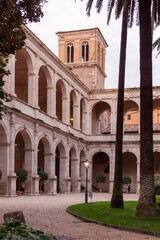 Obraz premium Entrance to the ecclesiastical enclosure with arches, columns and palm trees in the city of Rome