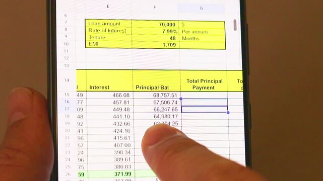 Man scrolling an excel sheet on the phone screen showing bank loan amortization table. Banking